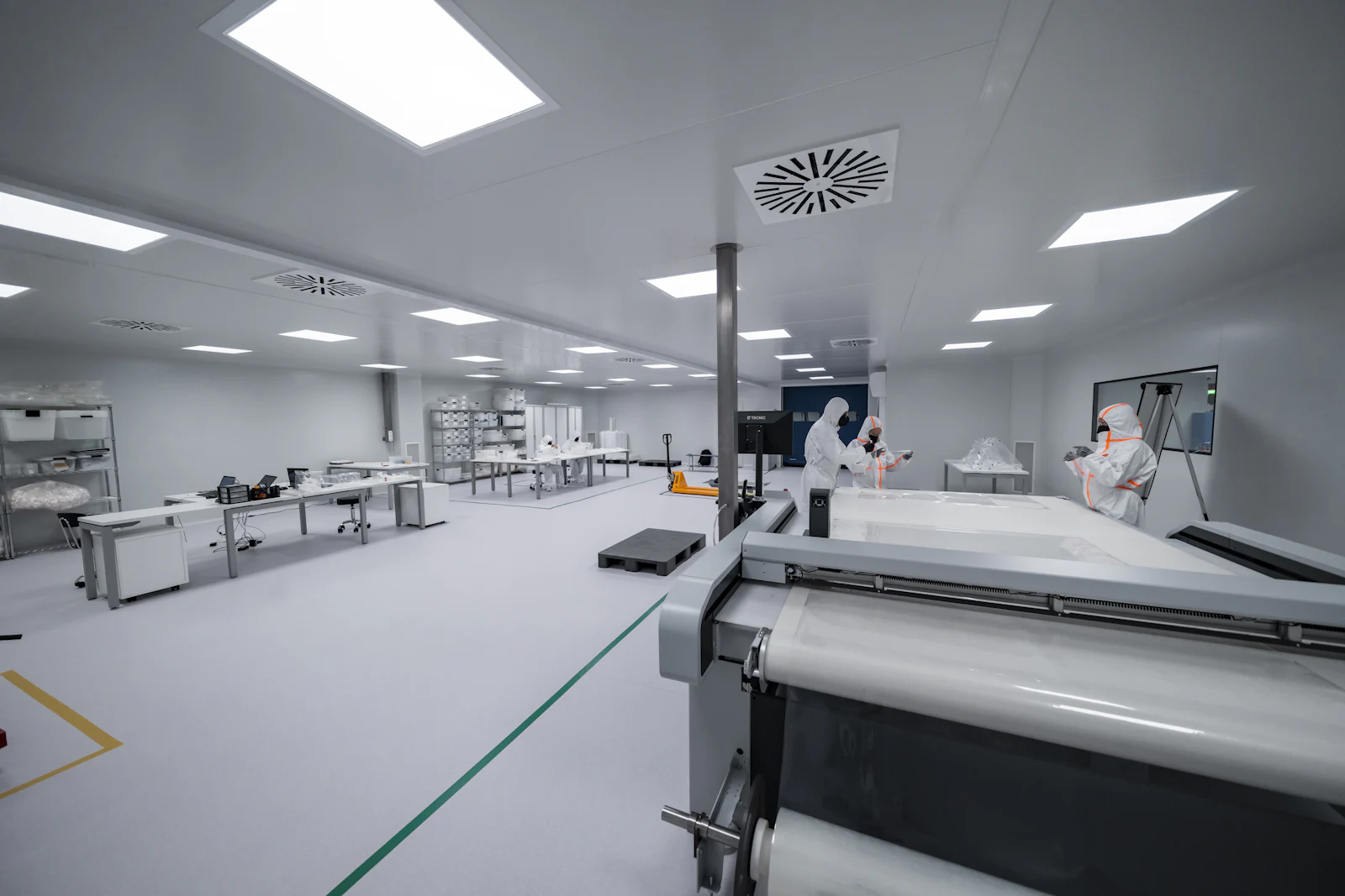 Engineers in cleanroom suits working in a bright semiconductor cleanroom